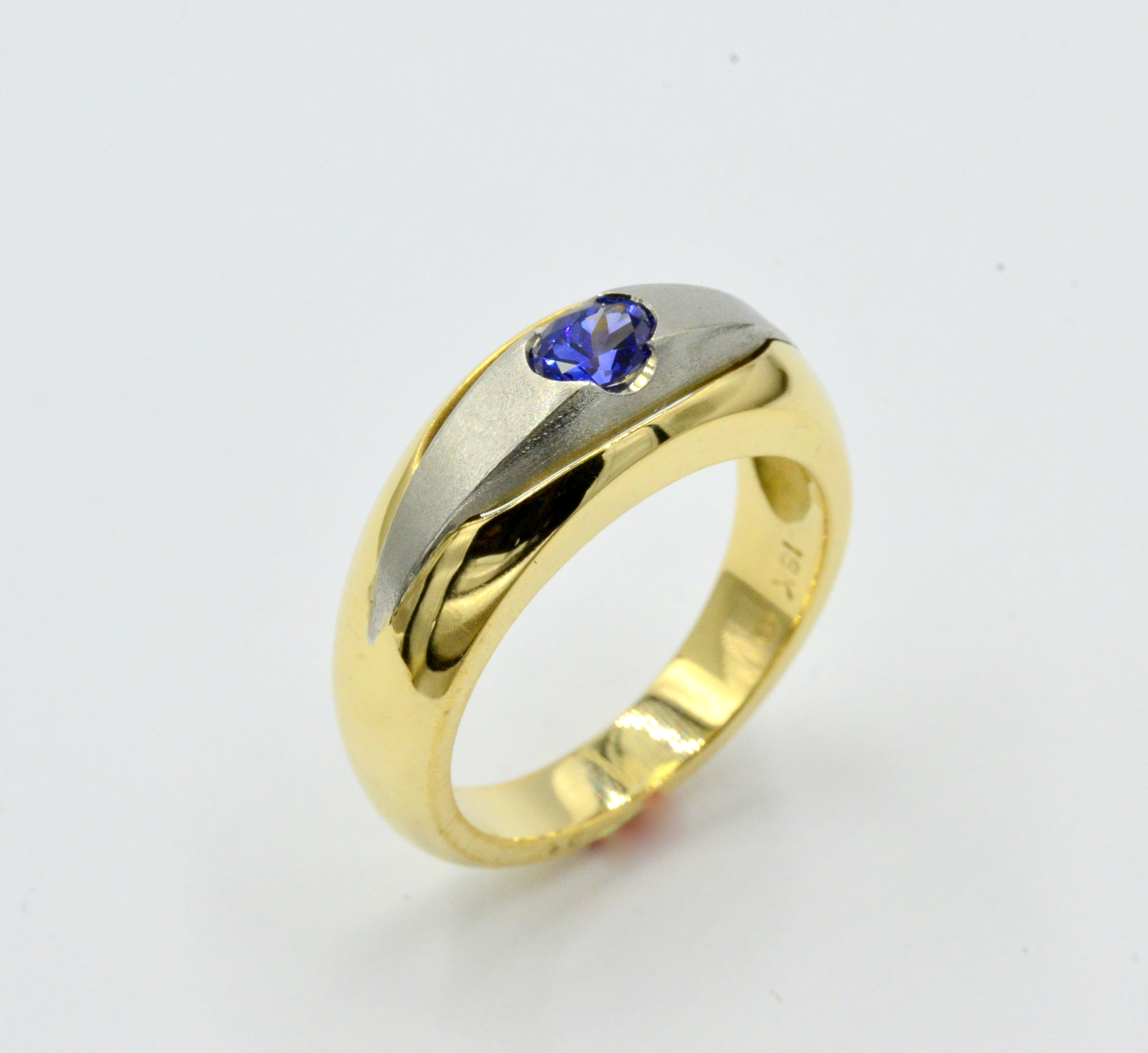 Beautiful Blue Sapphire set into a brushed white gold section. Flanked in rich 18 karat yellow gold .
